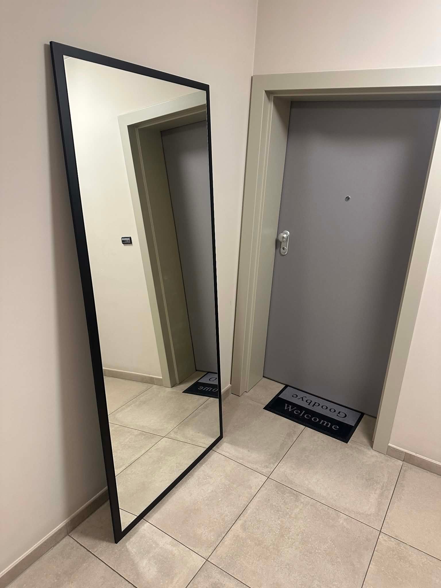 Miroir à effet flottant Glass Chaidron posé contre le mur dans une entrée